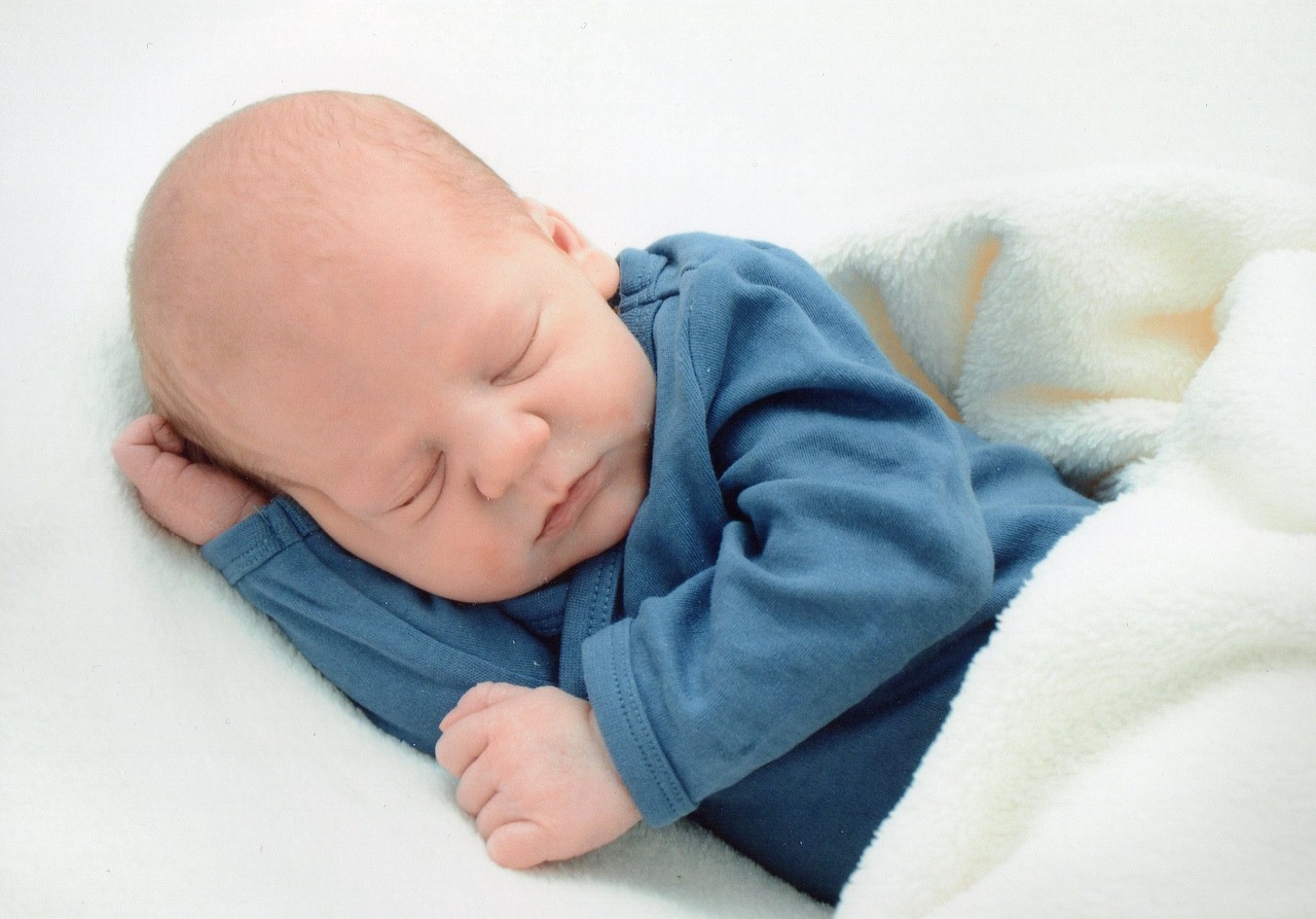 Bebé recién nacido niño en cama. Niño recién nacido duerme bajo